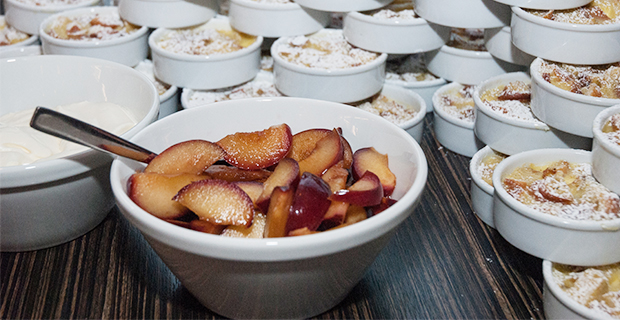 Överblivna kanelbullar används till julkryddad brödpudding som serveras tillsammans med inkokta plommon och vispad grädde.
